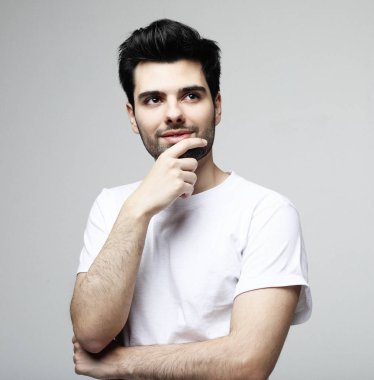 Akıllı rahat giyim yakışıklı genç esmer adam kamera bakarak, beyaz arka plan üzerinde