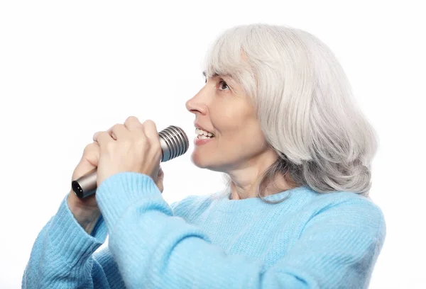 Estilo de vida, emoción y concepto de la gente: Feliz anciana cantando con micrófono, divirtiéndose, expresando talento musical sobre fondo blanco — Foto de Stock