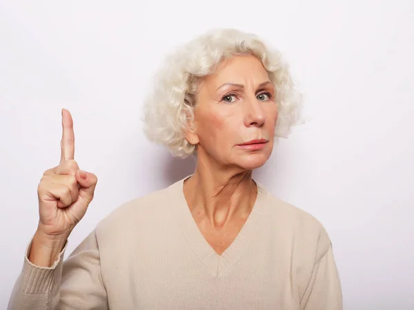 Myšlenka, pozornost a koncept lidí - portrét usměvavé starší ženy ukazující prstem nahoru na bílé pozadí — Stock fotografie