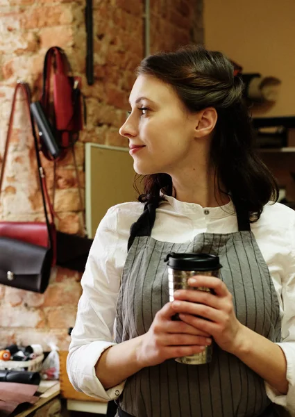 young master woman drinks coffee in a workshop, lunch break