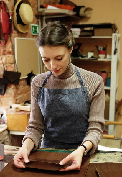 Jong brunette vrouw werkt in een zak maken studio, knipt uit details — Stockfoto
