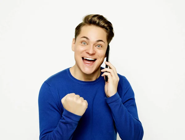 Happy young man in shirt gesturing and smiling while talking on the mobile phone — Stock Photo, Image
