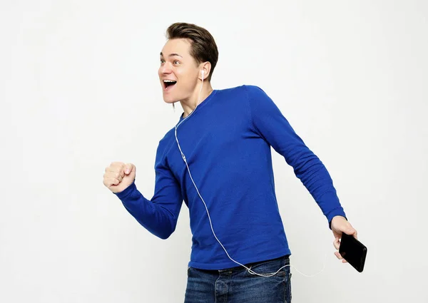 Feliz joven y elegante hombre ajustando sus auriculares y sonriendo mientras está de pie sobre fondo blanco — Foto de Stock