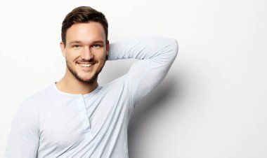 Akıllı, sıradan giyinmiş yakışıklı genç adam kameraya bakıyor.