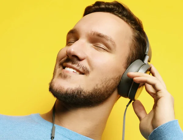 Hombre guapo lamiendo música sobre fondo amarillo —  Fotos de Stock