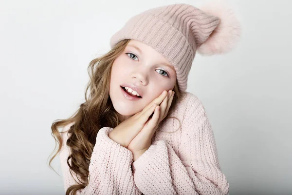 Persone, infanzia e concetto di moda: bambina che indossa cappello invernale rosa e maglione su sfondo rosa — Foto Stock