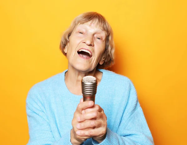 Estilo de vida y concepto de personas: Feliz anciana cantando con micrófono, divirtiéndose, expresando talento musical — Foto de Stock
