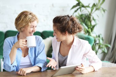yaşam tarzı, teknoloji ve insan kavramı: evde tablet bilgisayar kullanarak anne ve yetişkin kızı