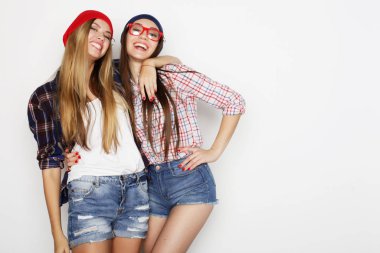 Yaşam tarzı ve insan konsepti: iki genç kız arkadaş bir arada duruyor ve eğleniyorlar. Hipster tarzı.
