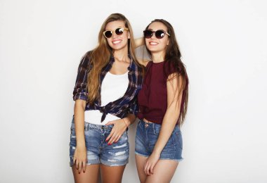 Yaşam tarzı ve insan konsepti: iki genç kız arkadaş bir arada duruyor ve eğleniyorlar. Hipster tarzı.