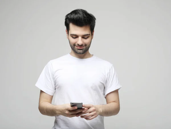 Junger Modemann trägt lässig tippende SMS auf grauem Hintergrund — Stockfoto
