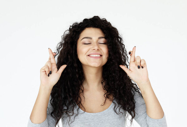 Радостная брюнетка женского пола, поднимает пальцы скрестив, загадывает желаемое
.