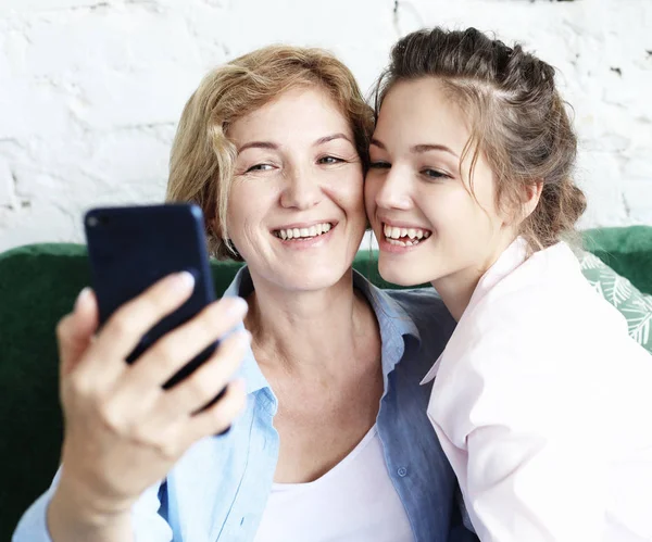 Спосіб життя, сім'я, технології та концепція людей: зріла мати та її дочка роблять селфі за допомогою смартфона — стокове фото