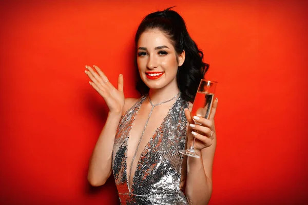 Joven mujer atractiva vestido de noche sosteniendo la copa de champán sobre fondo rojo . —  Fotos de Stock
