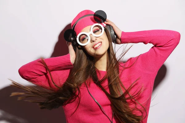 Hermosa joven con auriculares escuchando música de pie sobre un fondo gris —  Fotos de Stock