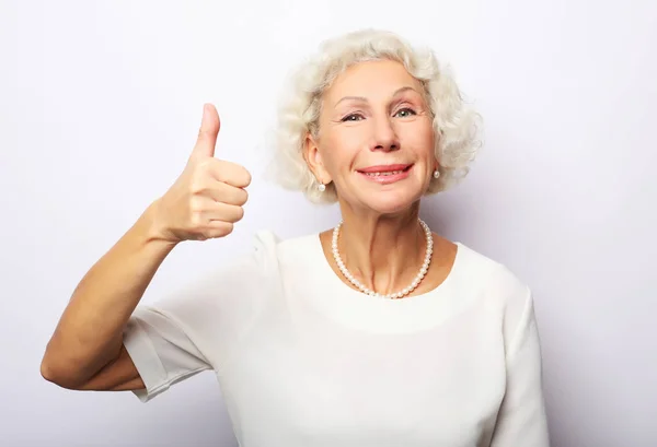 Lifestyle, emotion and people concept: Elderly happy woman giving a thumb up and looking at the camera — Stock Photo, Image