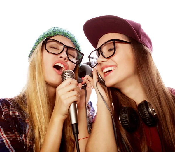 Спосіб життя, щастя, емоції та концепція людей: дві красиві дівчата з мікрофоном співають та розважаються — стокове фото