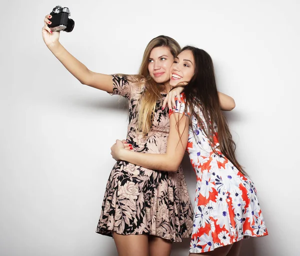 Образ жизни, мода и концепция людей: две молодые подруги стоят вместе, фотографируются и веселятся . — стоковое фото