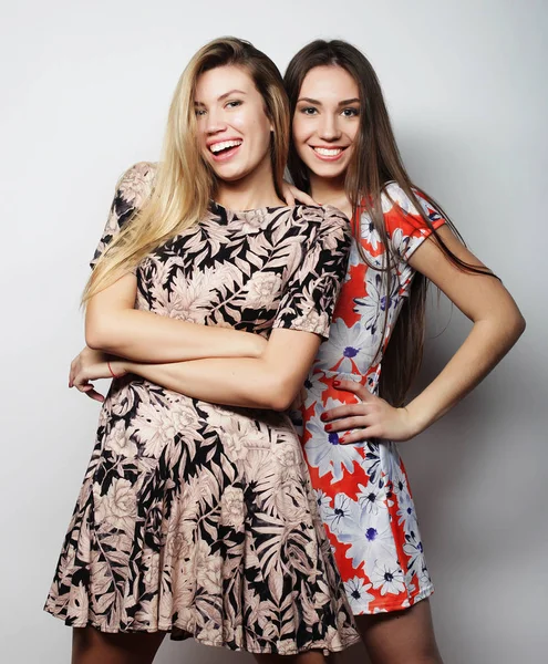 Lifestyle- und People-Konzept: zwei junge Freundinnen in Kleidern, die zusammen stehen und Spaß haben. Blick in die Kamera. — Stockfoto