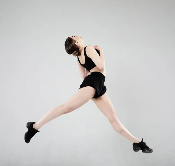 Spor, Fitness ve insan kavramı: güzel genç kadın spor elbise giymiş gri arka plan üzerinden atlama — Stok fotoğraf