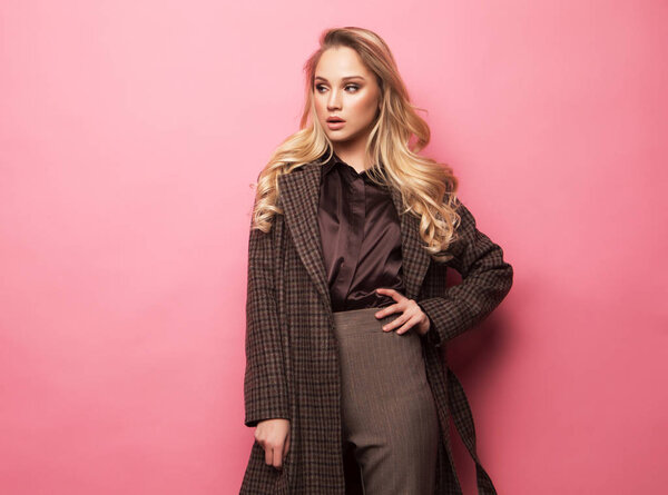 Fashion, people and lifestyle concept: Beautiful woman long blond curly hair wear cashmere coat over pink background