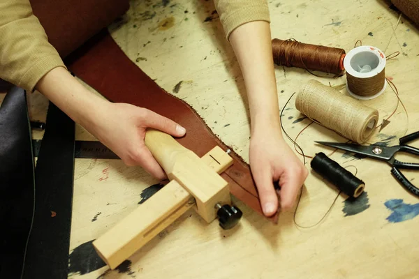 Молодая брюнетка работает в мастерской по изготовлению сумок, вырезает детали — стоковое фото