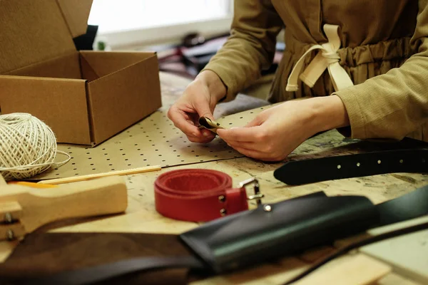 Junge brünette Frau arbeitet in einem Taschenstudio, schneidet Details aus — Stockfoto