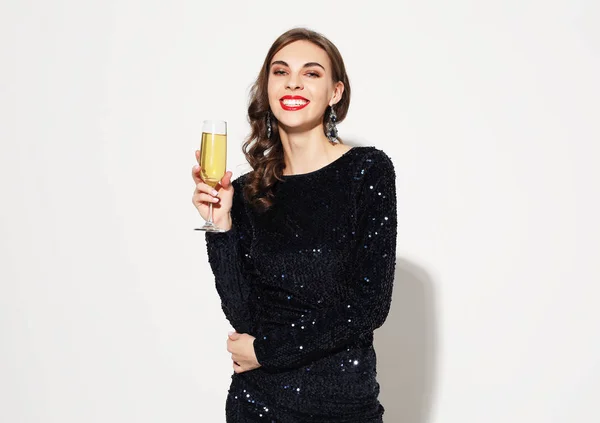 Luksusowa Kobieta w sukni wieczorowej trzymając kieliszek szampana stwarzające na białym tle — Zdjęcie stockowe