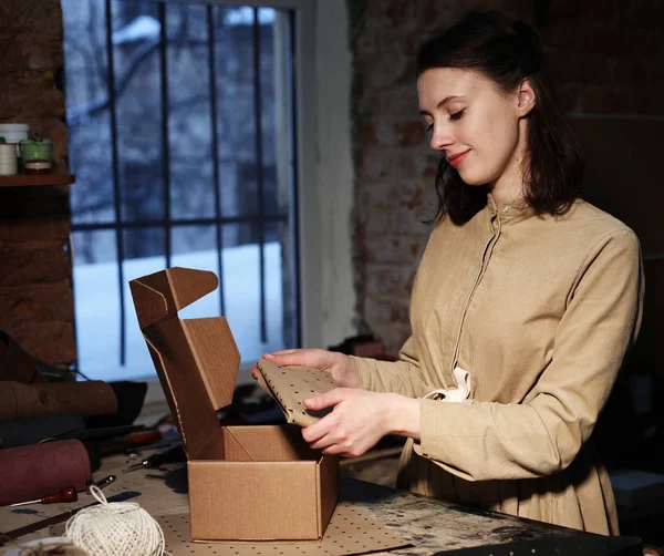 Młoda kobieta składa pudełko w warsztacie szycia — Zdjęcie stockowe