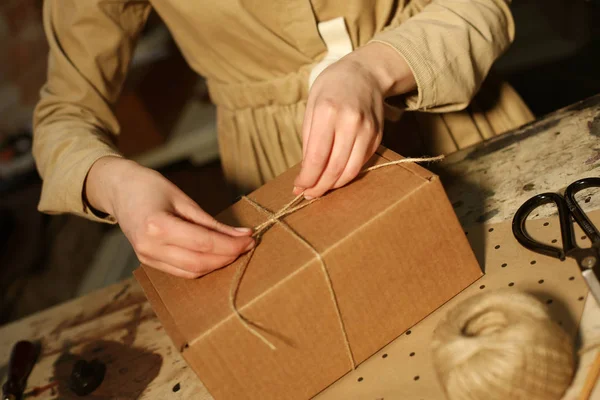 Giovane donna piega scatola di imballaggio nel laboratorio di cucito — Foto Stock