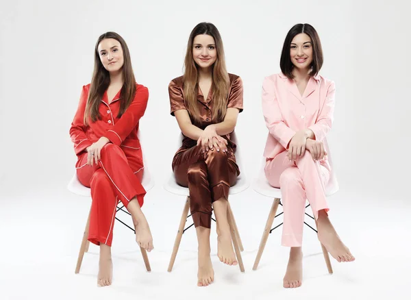 Pijama giymiş üç güzel kız arkadaş sandalyeye oturup kameraya poz veriyor.. — Stok fotoğraf
