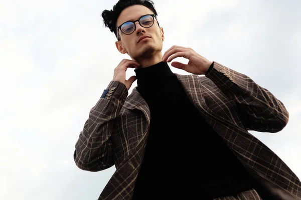 Seriózní mladý muž pózující pro reklamu nosí kulaté brýle, venkovní. — Stock fotografie