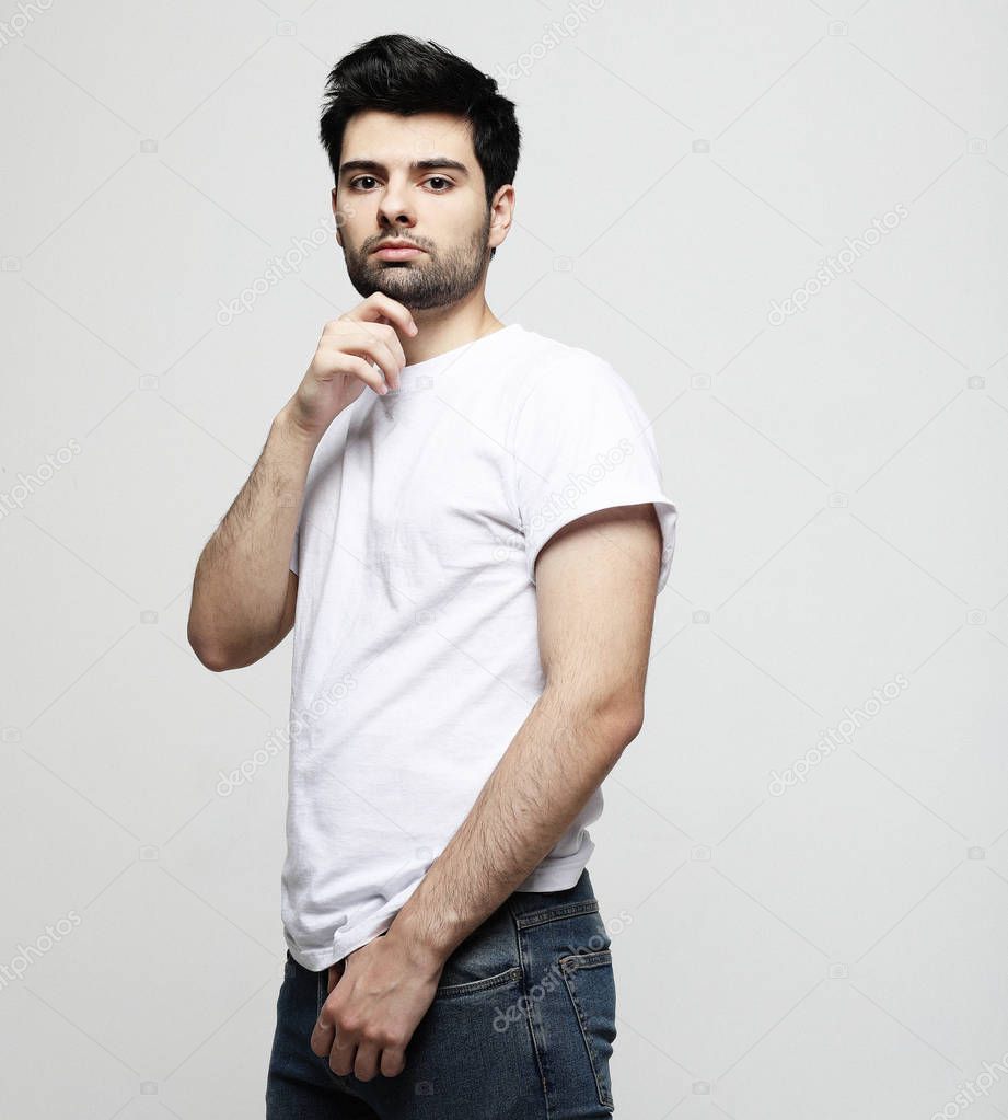 Handsome young man, fashion model, in smart casual wear looking at camera, over grey background