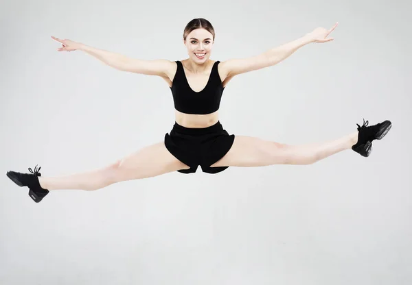 运动,健身和人的概念:美丽的年轻女子穿着运动服跳起灰色背景 — 图库照片