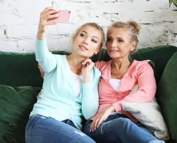 Спосіб життя, технології та концепція людей: зріла мати та її дочка роблять селфі за допомогою смартфона — стокове фото