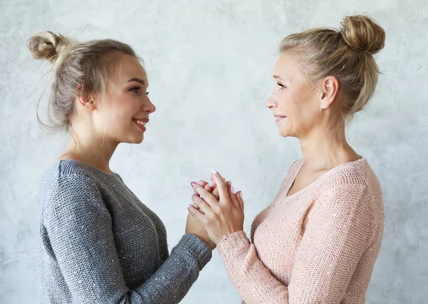 Beautiful senior mom and her adult daughter are hugging, looking at camera and smiling. At Home. — Stock Photo, Image