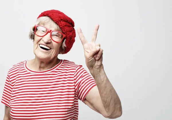 Vecchia donna ridere e mostrando la pace o la vittoria signat camera. Emozione e sentimenti. Ritratto della nonna espressiva. — Foto Stock