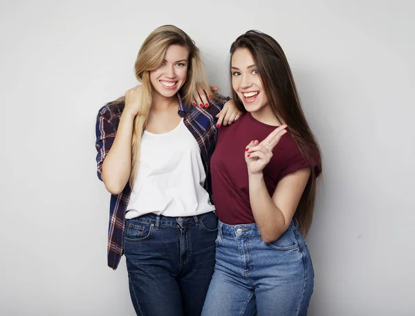 Estilo de vida y el concepto de la gente: Dos amigas jóvenes de pie juntos y divirtiéndose. Mirando la cámara. —  Fotos de Stock