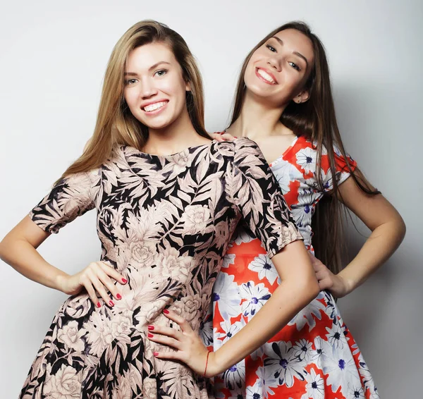Lifestyle, fashion and people concept - two stylish sexy girls best friends wearing dress over white background — Stock Photo, Image