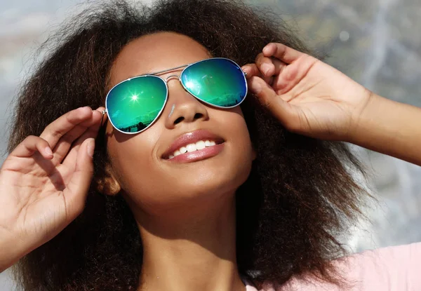 Bonita mujer con gafas de sol con dientes perfectos y piel oscura y limpia descansando al aire libre — Foto de Stock