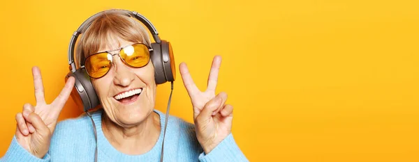 Zabawna staruszka słuchająca muzyki i pokazująca kciuki w górze. — Zdjęcie stockowe