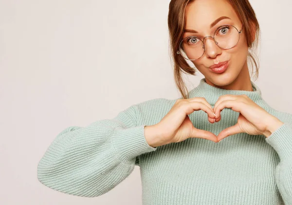 Hermosa chica haciendo corazón por manos aisladas sobre un fondo blanco — Foto de Stock