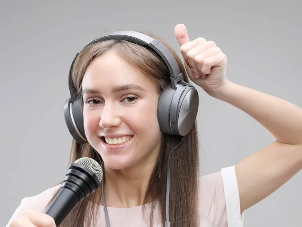 Ekspresyjna dziewczyna śpiewa z mikrofonu i słuchawek — Zdjęcie stockowe