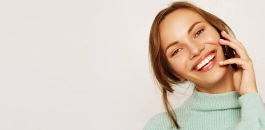  Güzel, neşeli bir kadın cep telefonuyla konuşuyor.