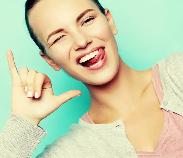 Смішна дівчина показує язик, позуючи на фоні студії. Емоційні позитивні молоді жінки роблять обличчя — стокове фото