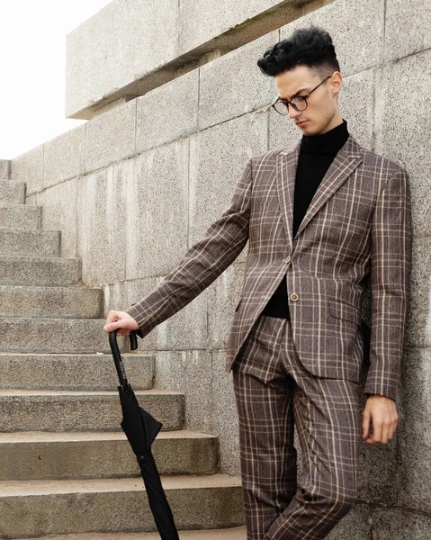 Fashionable young man in glasses with umbrella standing on the stairs — Stock Photo, Image