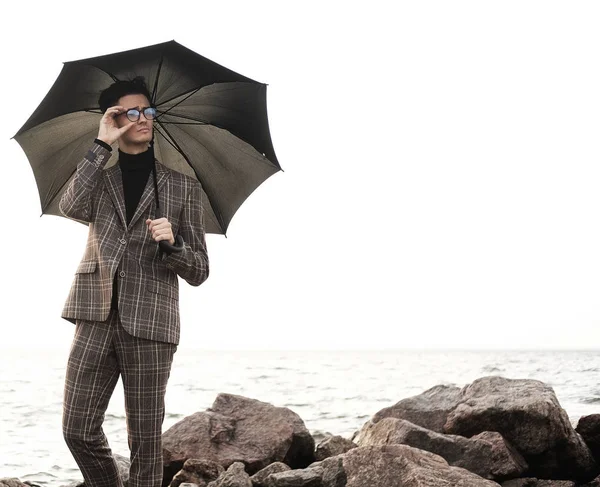 Giovane alla moda con ombrello in piedi vicino al mare — Foto Stock