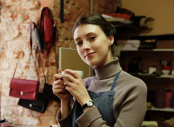 young master woman drinks coffee in a workshop, lunch break