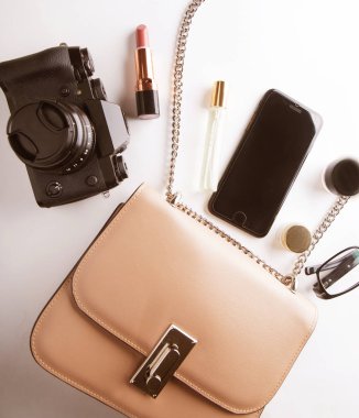Beyaz arka plan üzerinde kadın bej çanta aksesuarları smartphone, kozmetik, lasses, kamera ve parfüm ile Üstten Görünüm.