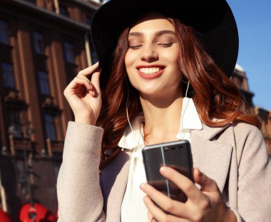 rahat tarzı giyinmiş güzel genç kız - ceket ve şapka, müzik dinleme